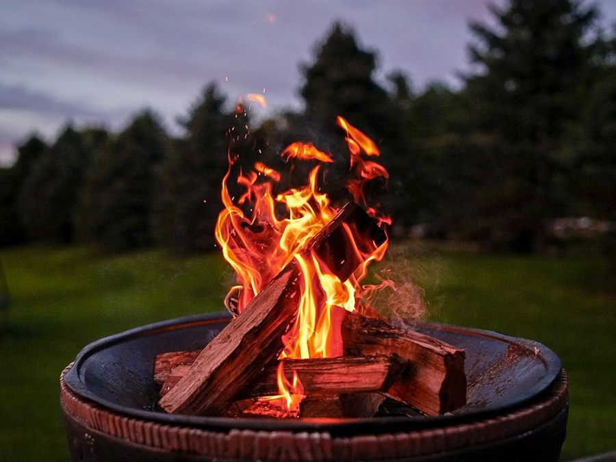 A wood fire burning in a round backyard fire pit at dusk