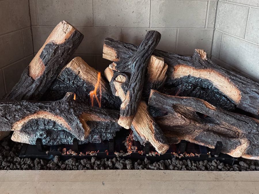 An oak-style gas log set burning on a grate in a showroom firebox