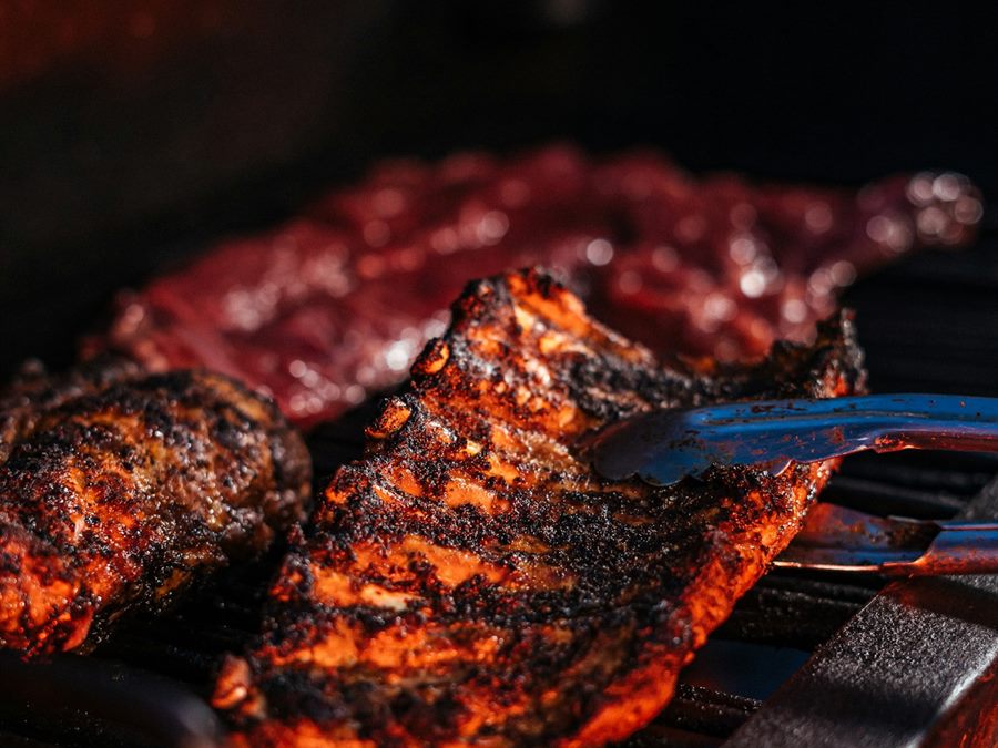 Ribs and chicken searing over the grates of a covered gas grill