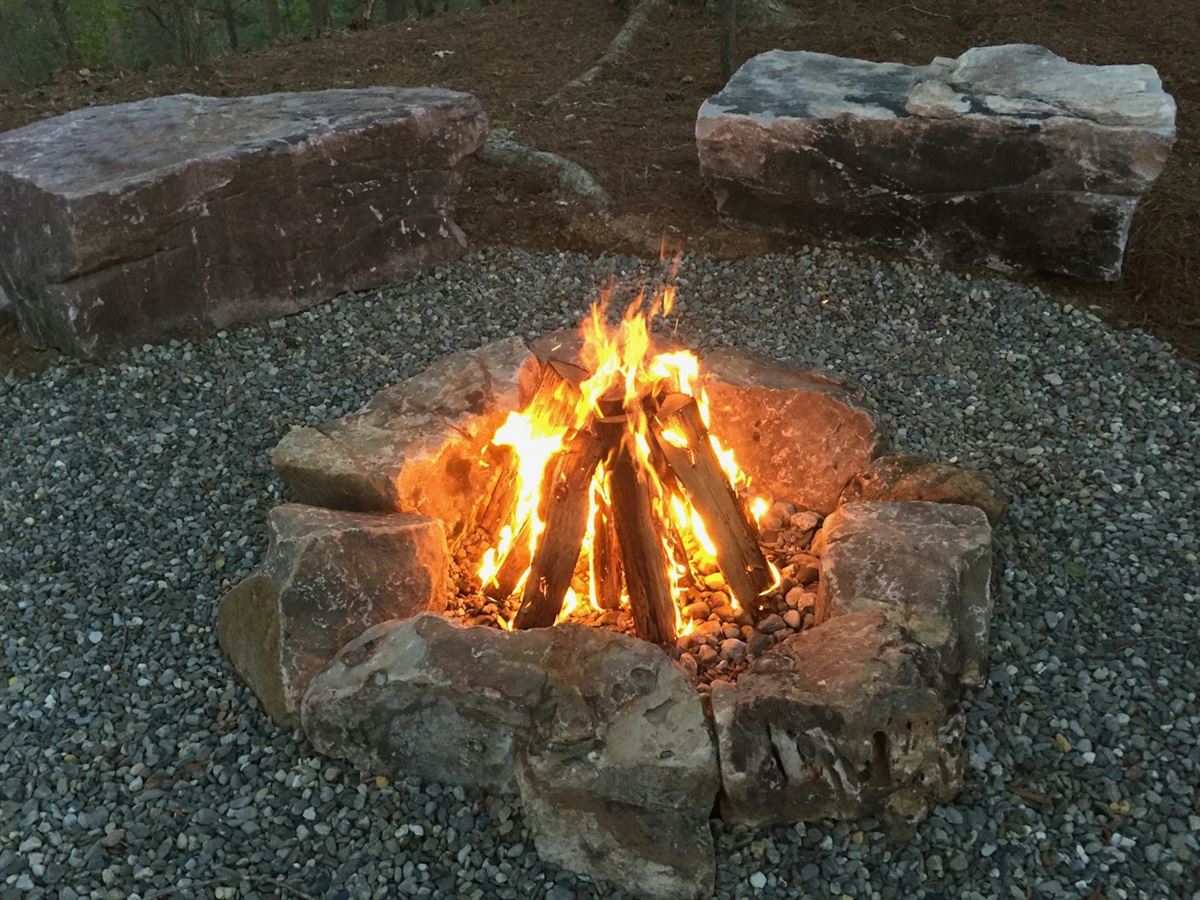 A stone-ringed fire pit burning at dusk with cut-stone seating around it