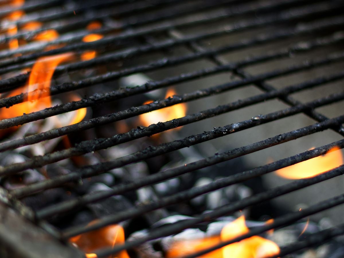 Flames rising through the cast grates of a charcoal grill