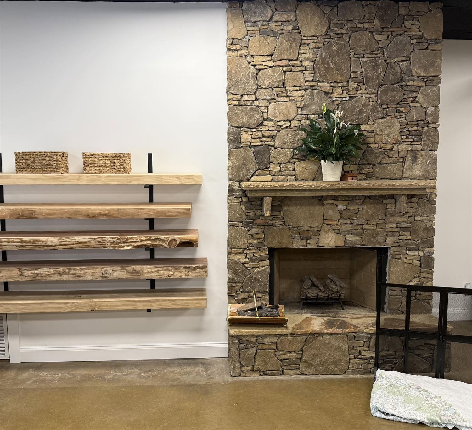 Inside the Hearth Enterprises showroom in Rome, Georgia: a stacked-stone fireplace display beside a wall of live-edge wood mantels