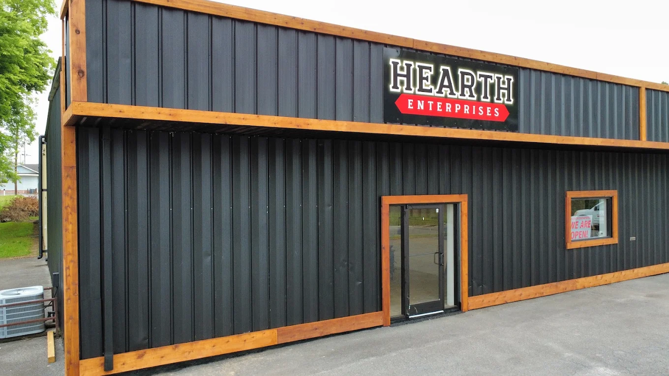 The Hearth Enterprises building on Holmes Avenue: black steel siding with cedar trim and a lit Hearth Enterprises sign
