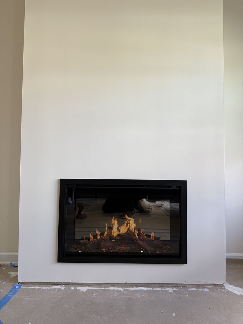 A long low contemporary gas fireplace set flush into a plain white wall, lit