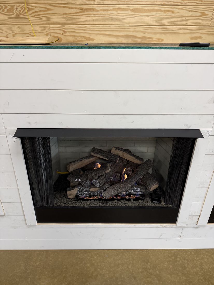 A white shiplap chimney breast with a black firebox and a gas log set, unlit